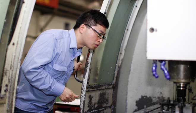 在銑削加工中心，陳閏祥正檢查零件狀況。 資料圖