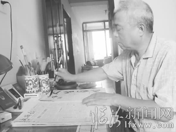 李楓正在報(bào)紙上練習(xí)寫毛筆字。