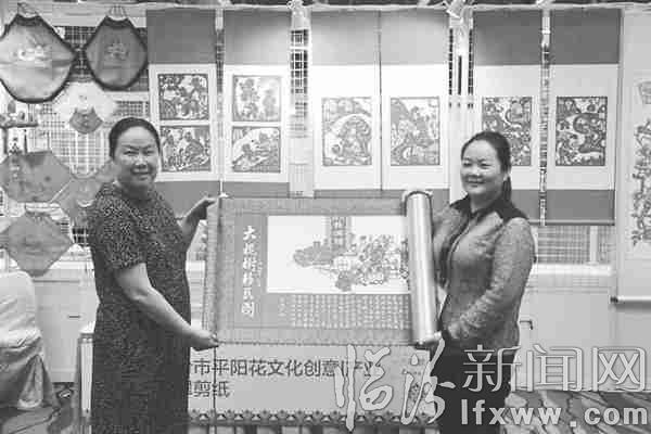 郝小翠(右)展示她的剪紙作品《大槐樹移民圖》。(圖片由本人提供)