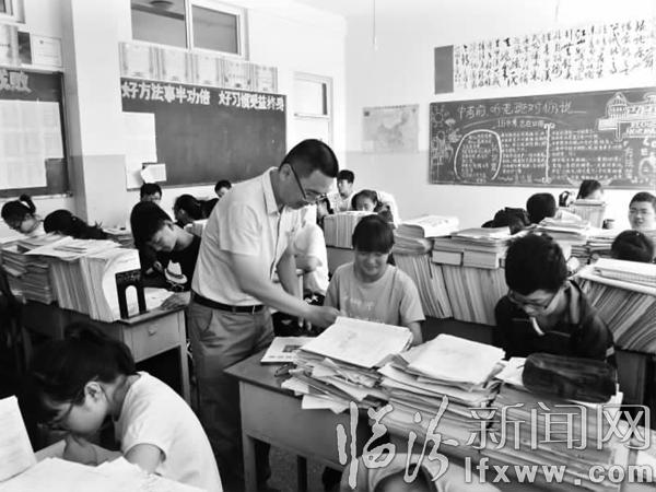 譚志俊給學生輔導作業。