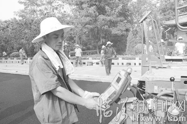 施工人員邊觀察鋪油設備儀表,邊進行道路鋪油作業