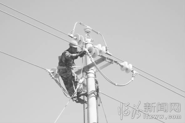圖為電力工人正在線桿上架設(shè)電線