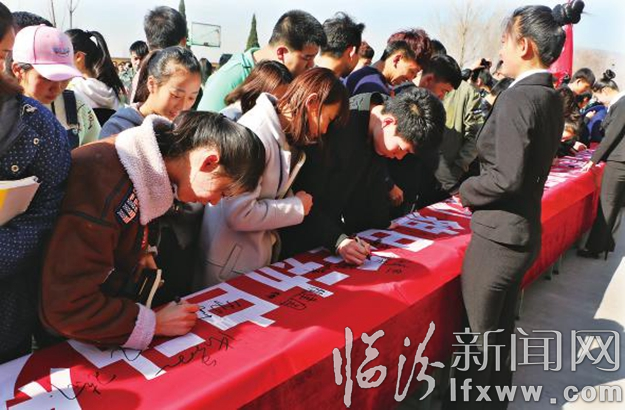 同學們在“青春,與文明同行”條幅上簽名